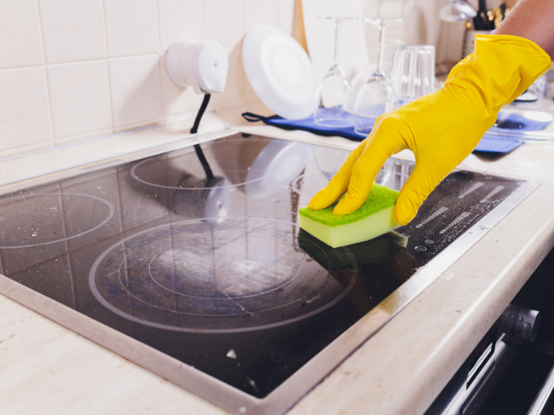 Cleaning a glass stovetop with a sponge and gloves